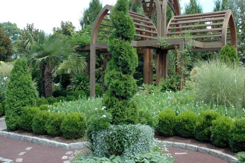 The visitor's eye is directed upward by narrow conifers and the peaked roof line of the arbor in this intimate area at the Sarah P. Duke Gardens in Durham, North Carolina.